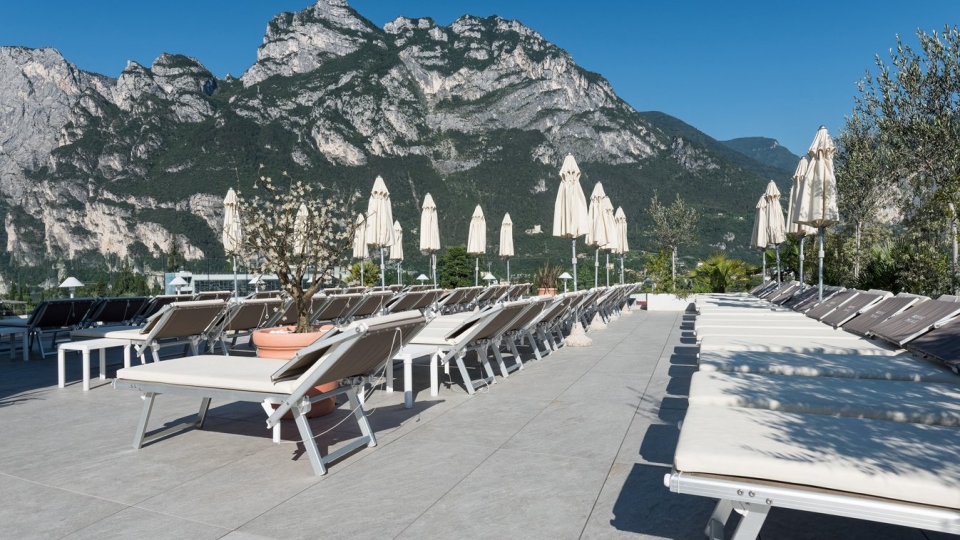 Mountain view lounge area with an Mbrico Tile Deck featuring sunbeds and umbrellas on a sunny terrace, perfect for relaxation and leisure in a scenic outdoor setting.